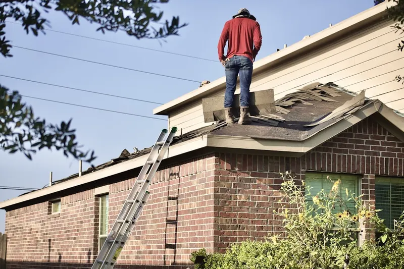 Professional roofer working on a residential roof in Plandome Manor